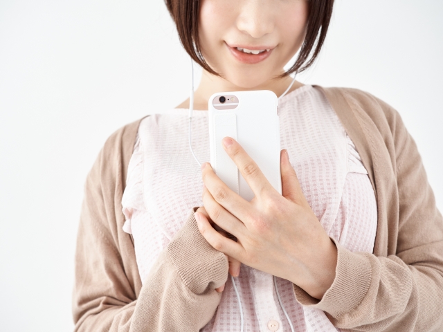 画像：スマートフォン画面を見て微笑む女性